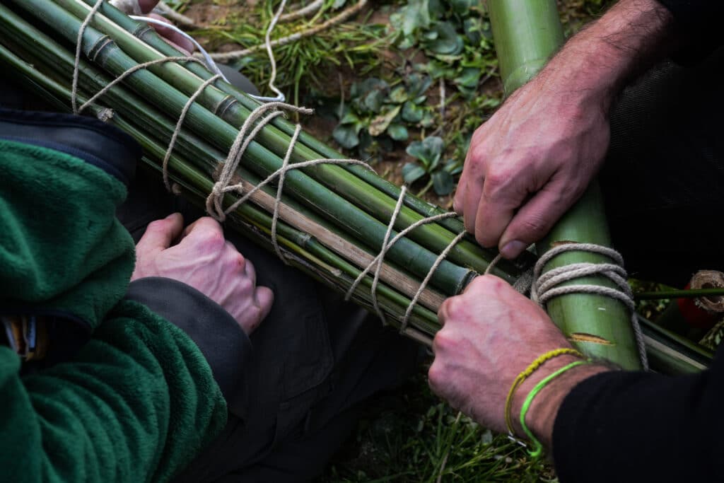 Dettaglio di mani che stringono un nodi su archi di bambù